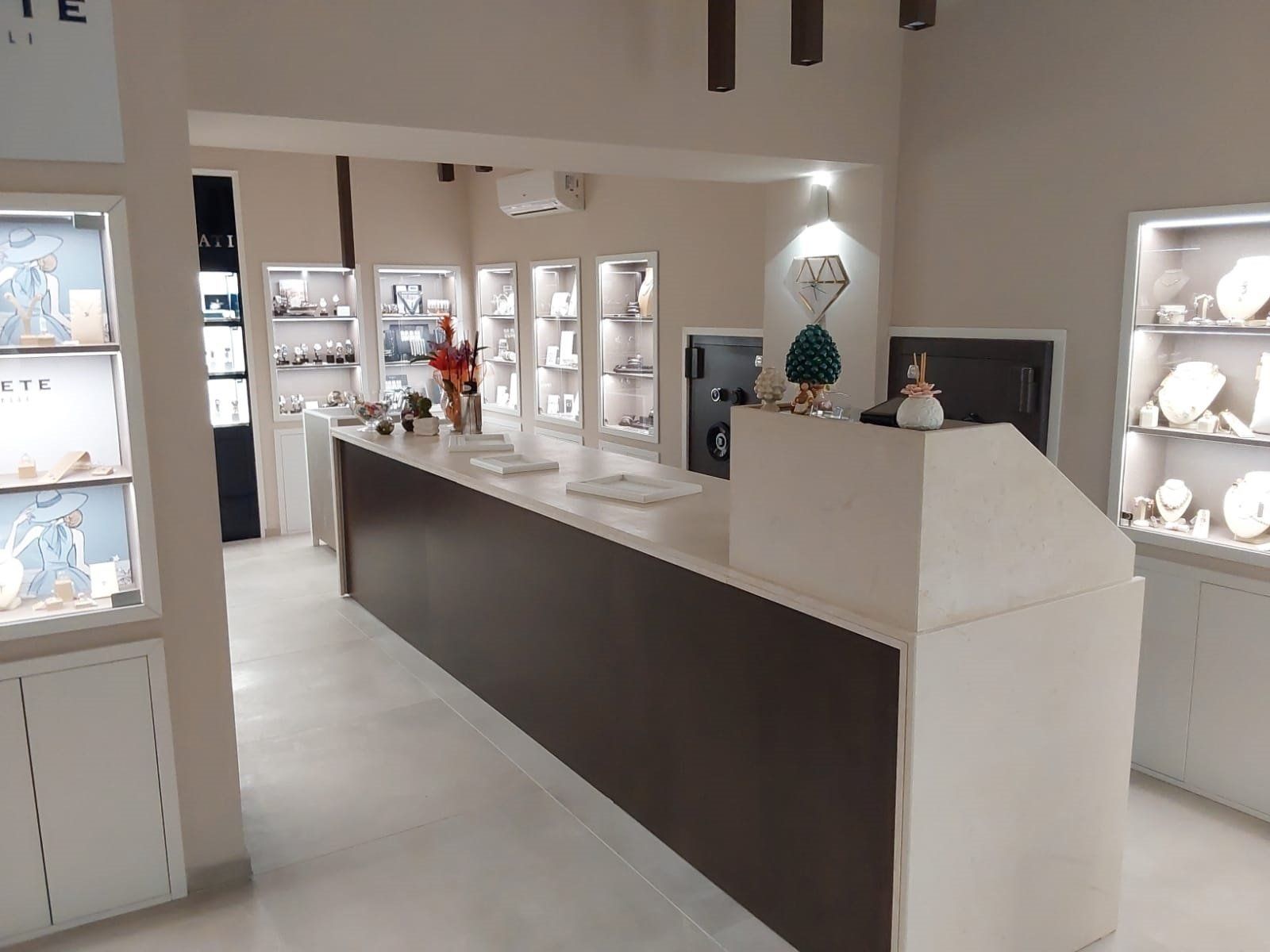 Interno di una gioielleria con vetrine, un lungo bancone e colori neutri.