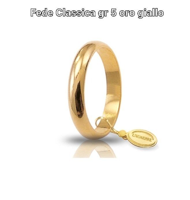 Fede nuziale in oro giallo con targhetta attaccata, su sfondo bianco.
