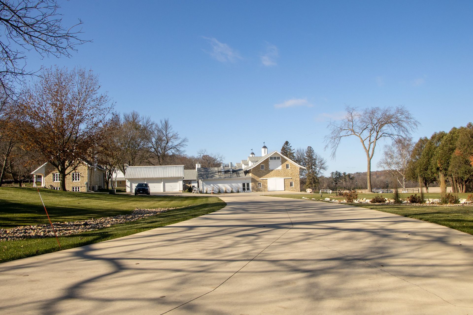 Empty suburban street leading to houses and trees under a clear blue sky