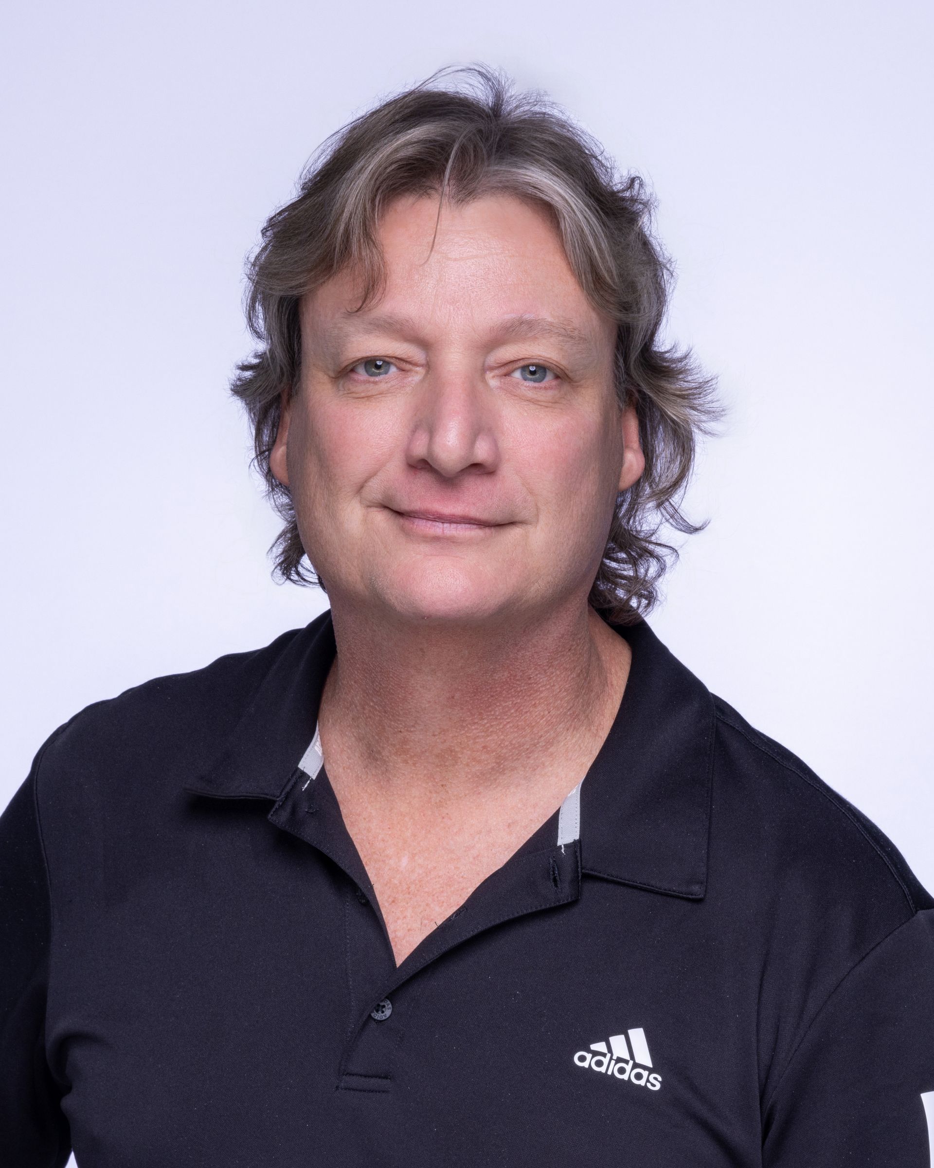 A man wearing glasses and a blue shirt is smiling for the camera.