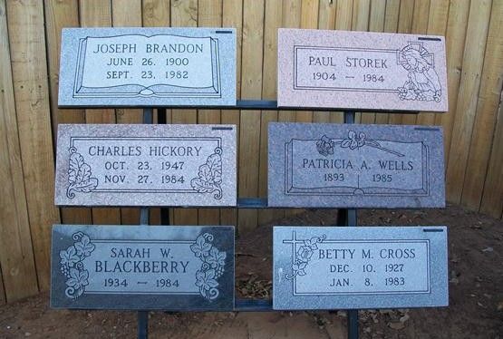 Six engraved memorial plaques arranged in two columns on a wooden wall.