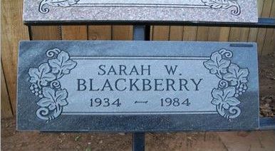 Gray gravestone plaque reading “Sarah W. BlackBerry 1934–1984” with floral carvings