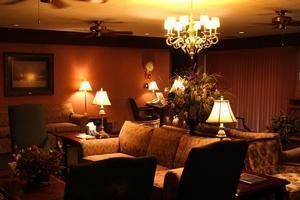 Cozy living room with warm lighting, chandelier, sofa, lamps, and framed wall art