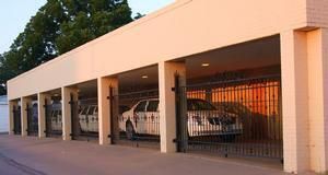 Covered parking area with cars behind barred openings at sunset