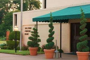 Hotel entrance with teal awning and topiary plants in orange pots