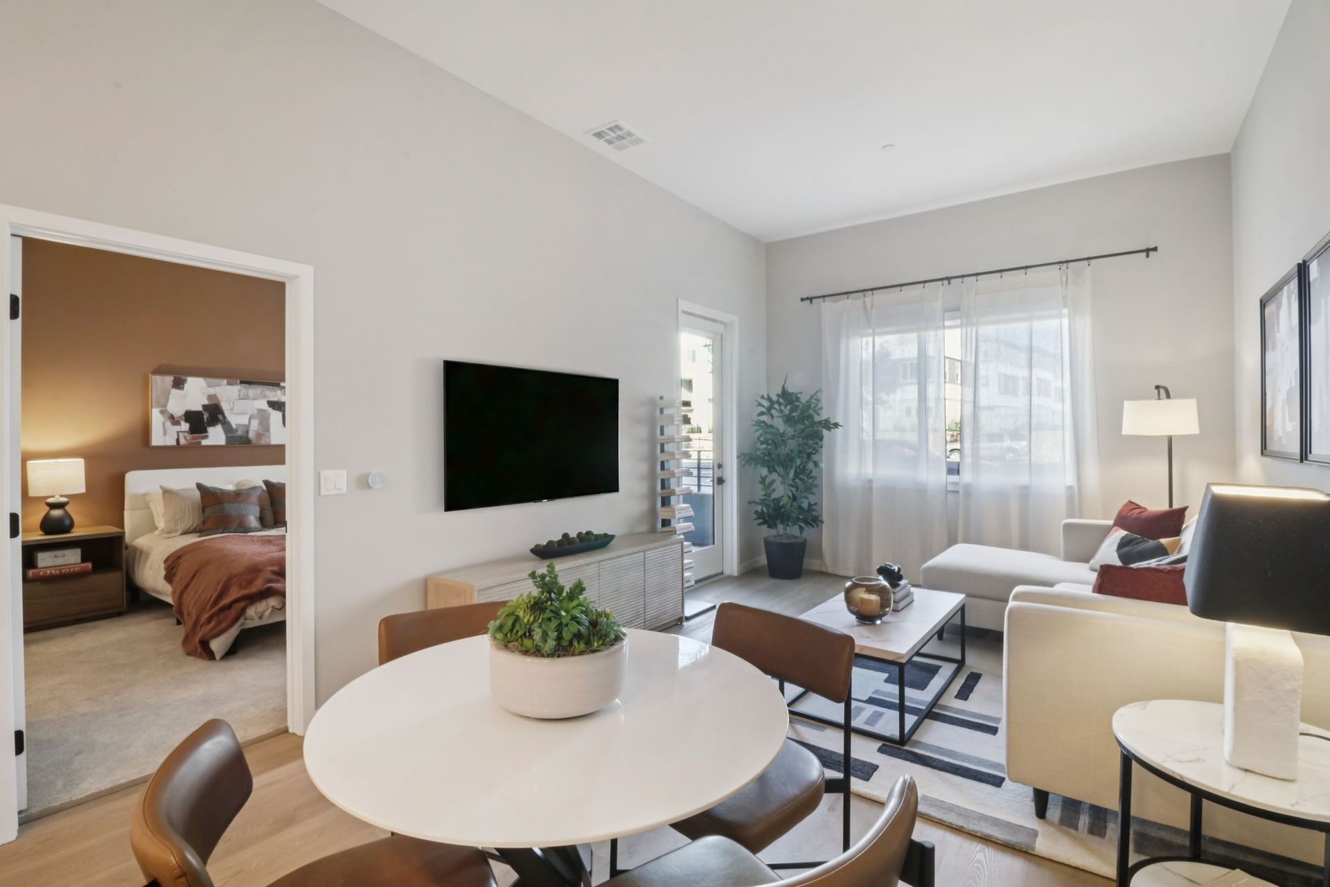 Living room and dining area with furniture, TV, and open doorway to bedroom.