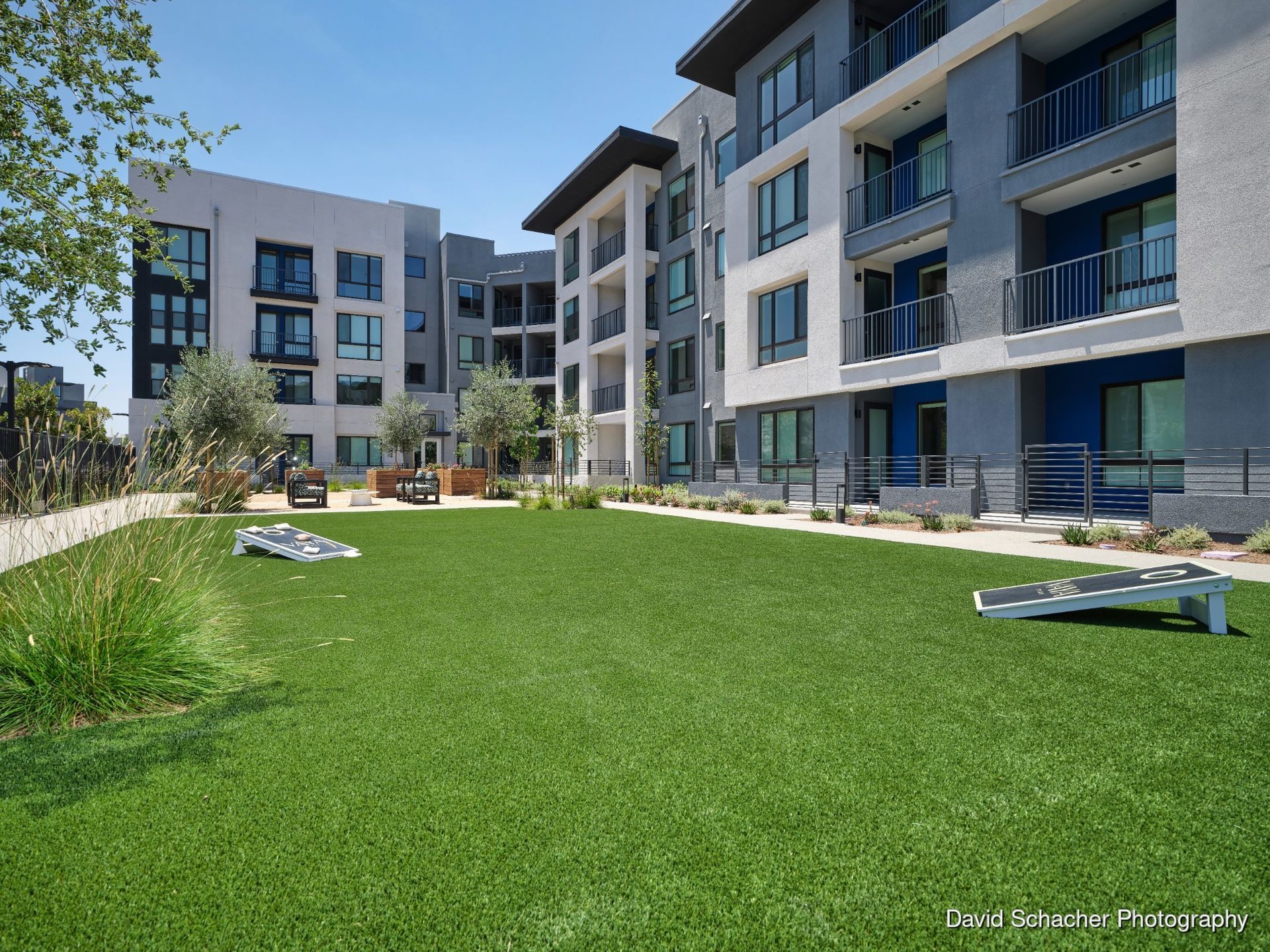 Apartment courtyard with green lawn, pergolas, and modern buildings under a cloudy sky