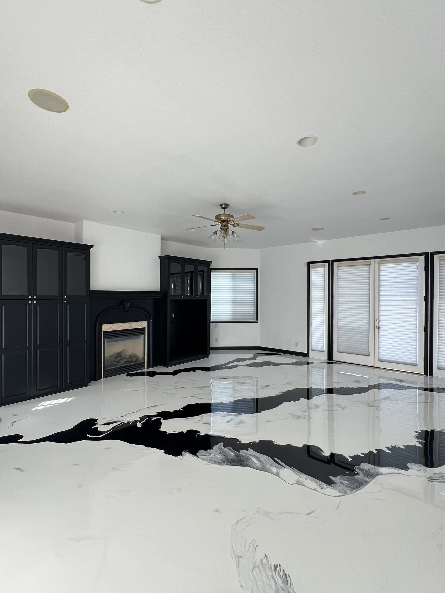 Modern empty living room with black cabinets, white walls, and sliding glass doors overlooking a patio