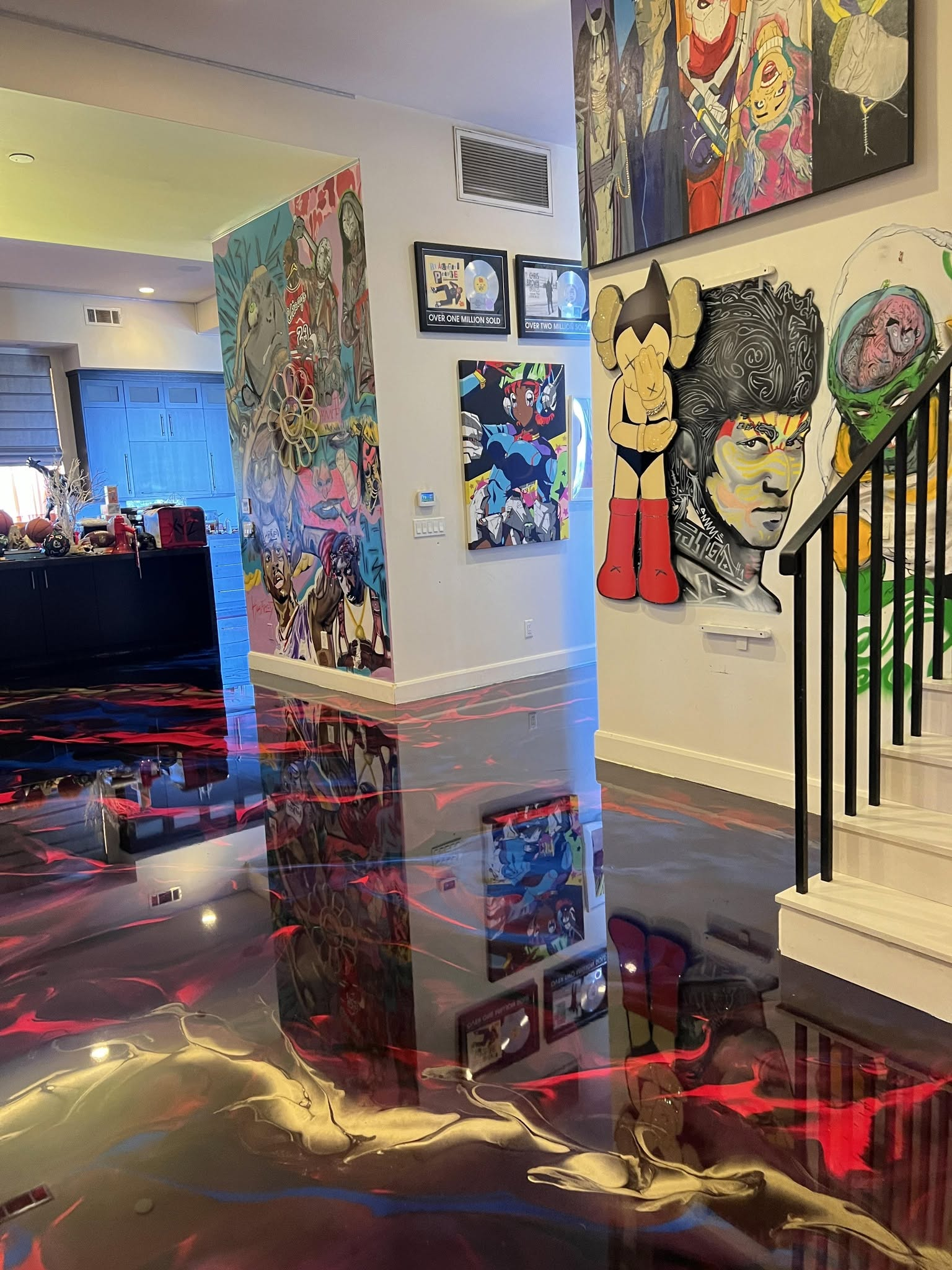Colorful modern home interior with large pop-art paintings and a glossy floor reflecting red and gold lights