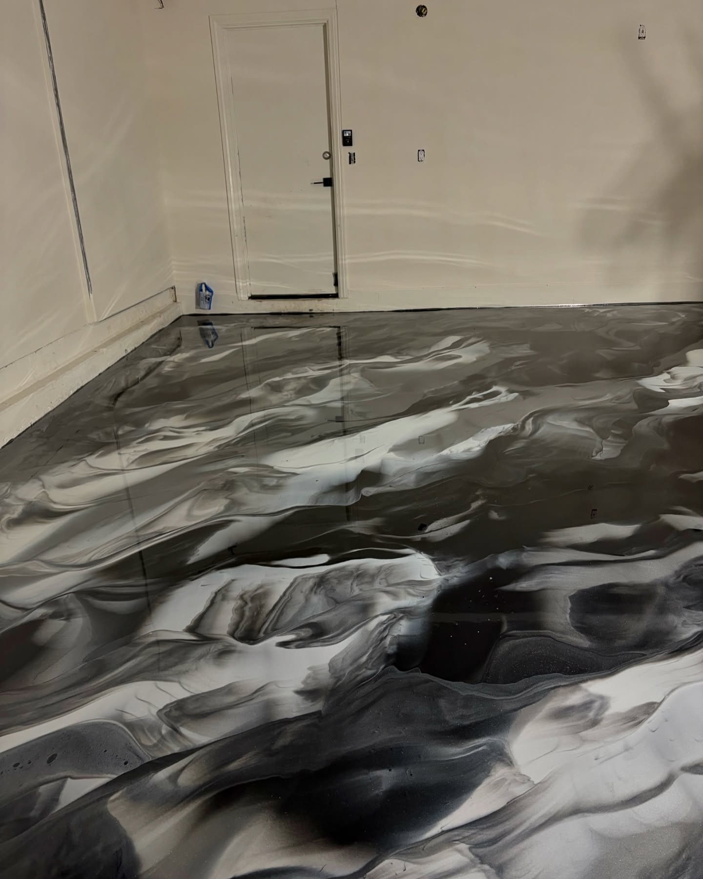 Empty room with white walls and a black-and-white marbled floor pattern