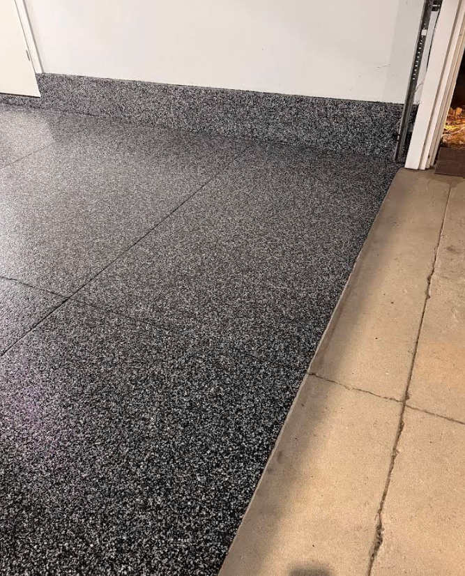 Speckled dark flooring meets tan tile at a doorway threshold