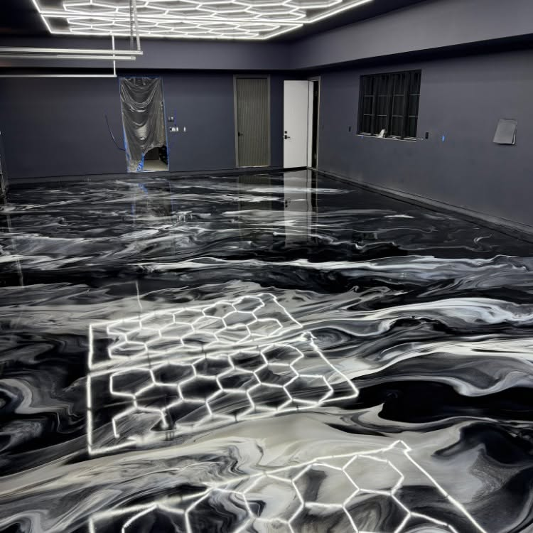 Empty room with glossy black-and-white marbled floor and white geometric patterns, gray walls, and overhead lights