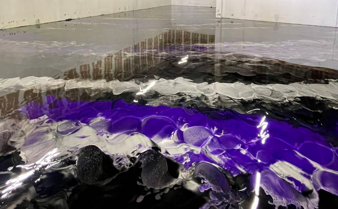 Purple and black abstract material layered in a glossy, textured installation with clear vertical panels above