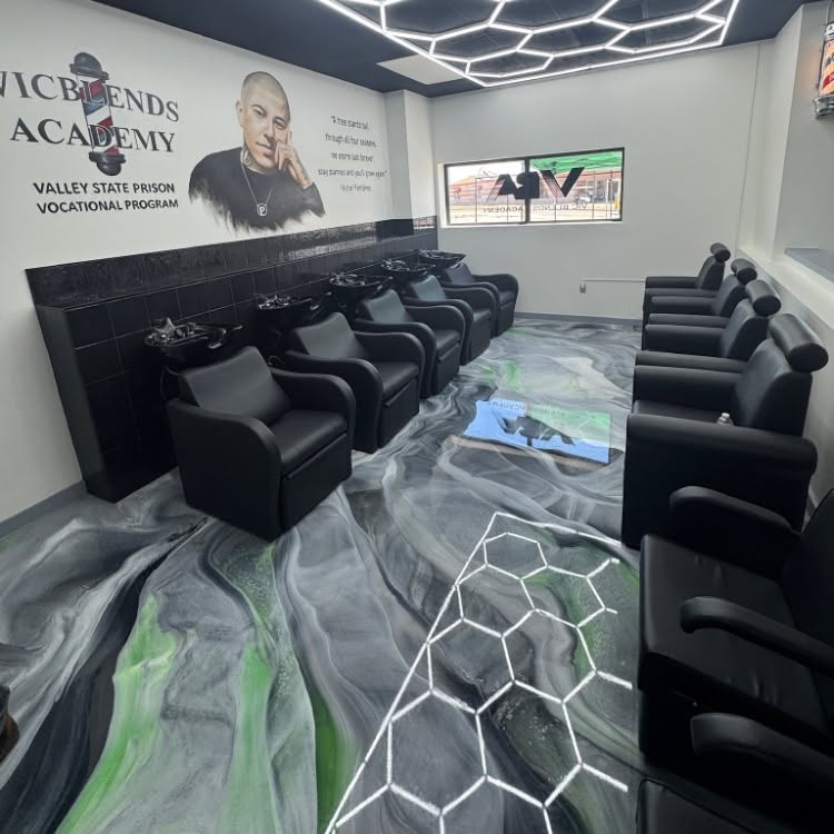 Black salon with rows of chairs, mural wall art, and gray-green geometric floor design