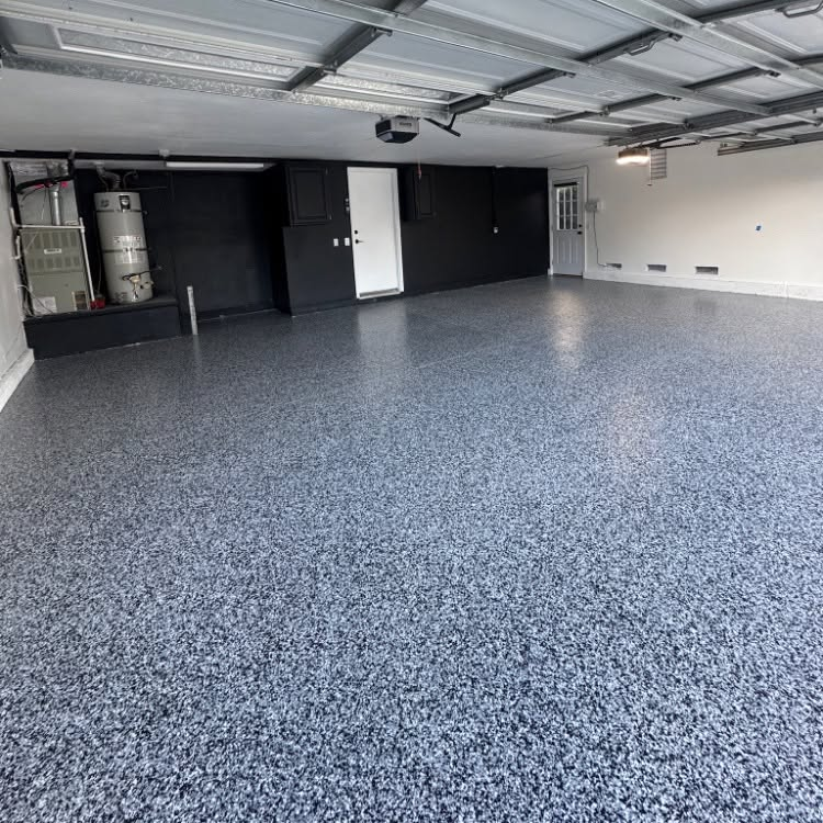 Empty garage with speckled gray floor, black walls, and overhead lights