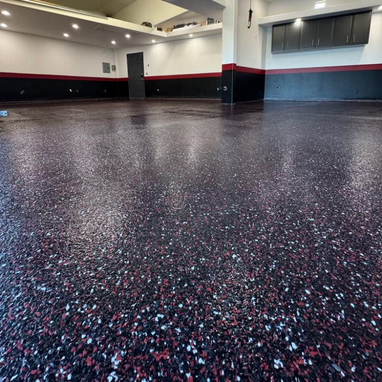 Empty gym with speckled black rubber flooring and gray walls with red trim