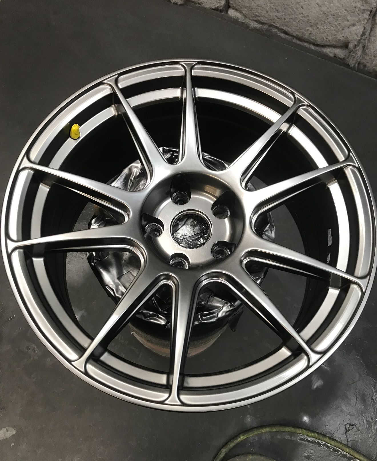 Shiny silver and black alloy car wheel with ten spokes.