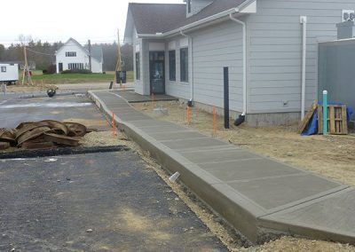 A concrete walkway is being built in front of a house.