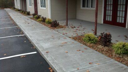 A sidewalk leading to a parking lot with a building in the background