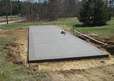 A large concrete slab is sitting in the middle of a dirt field.