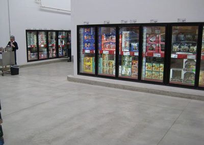 A man is standing in front of a row of refrigerators in a store.