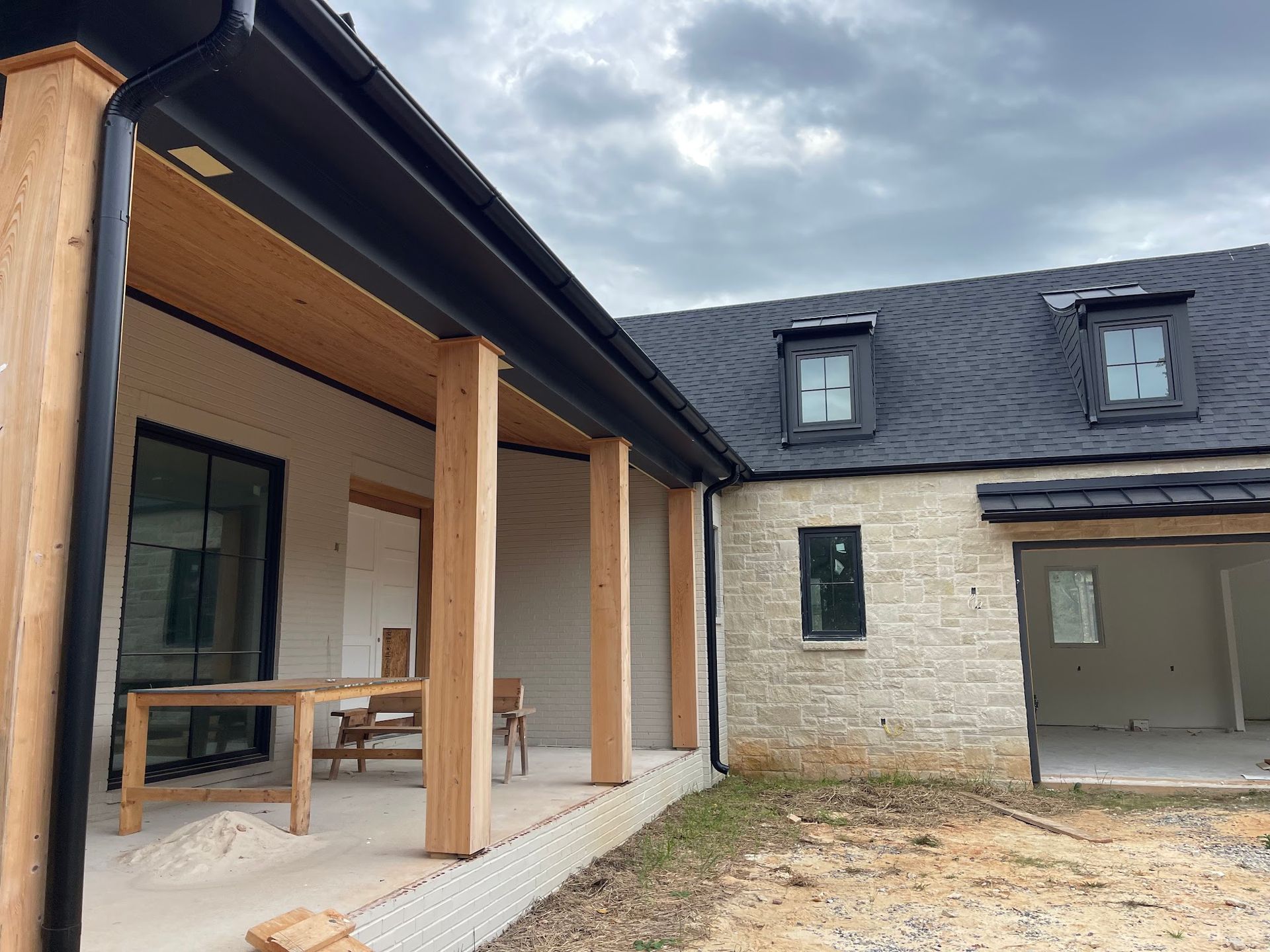A house with a porch and a black roof is being built.