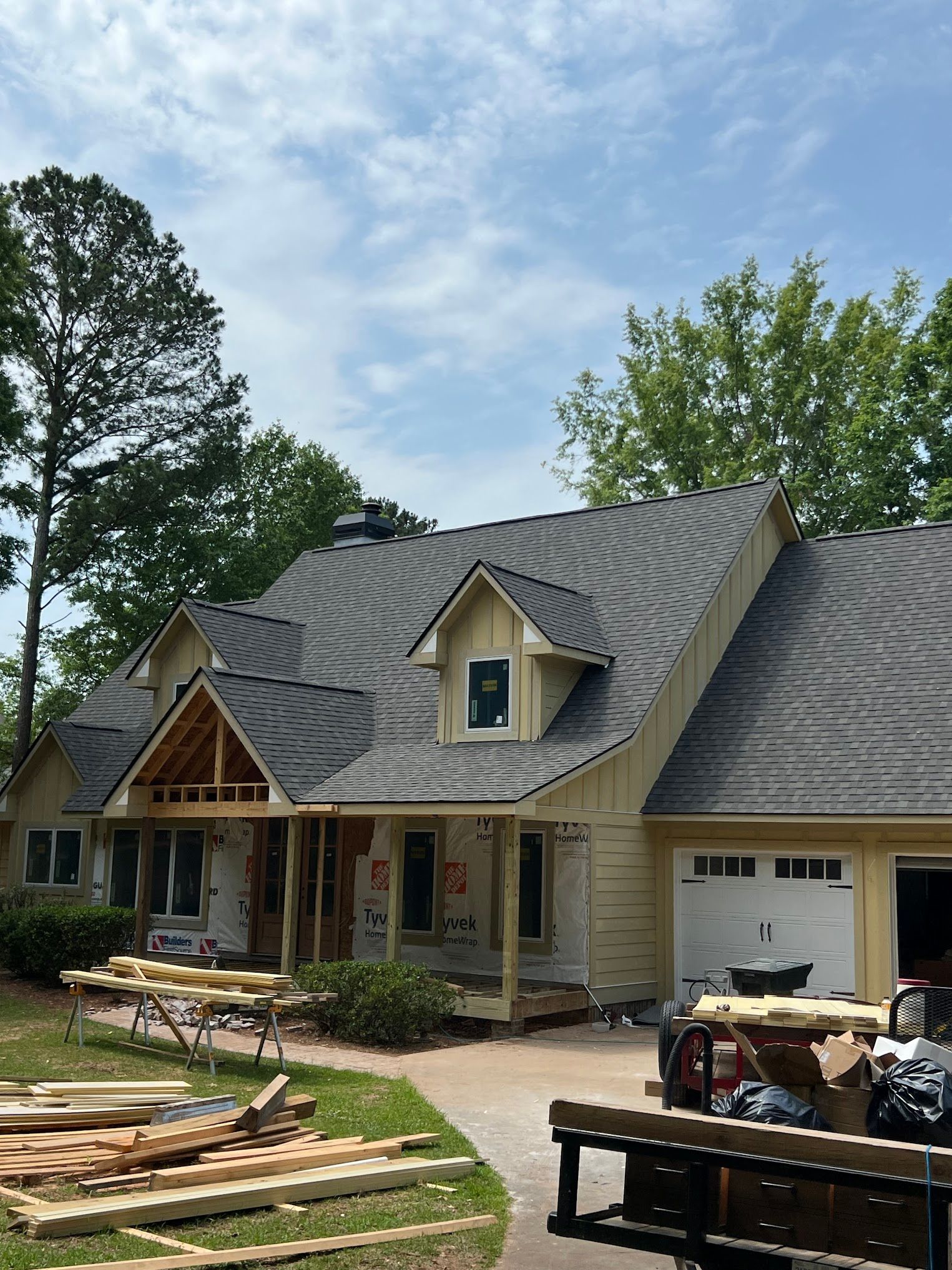 A large house with a gray roof is being built.