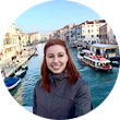 Une femme sourit à Venise, en Italie. Un canal avec des bateaux et des bâtiments se dessine à l'arrière-plan.