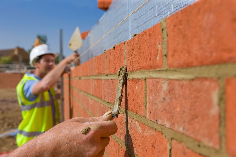 Construction worker applying mortar to a brick wall on a building site