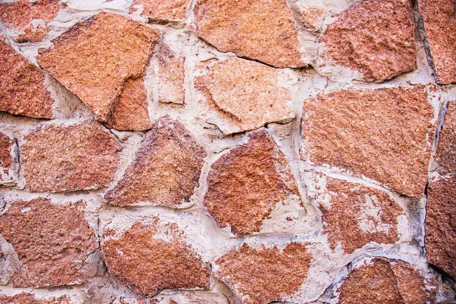Close-up of a rough stone wall with pink, tan, and white rocks and mortar