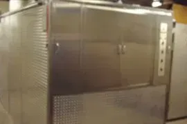 Large stainless steel industrial cabinet with double doors and a perforated lower panel in a utility room