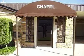 Chapel entrance with brown awning and glass doors in a brick building.