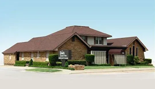 Single-story brick office building with a brown roof and covered entrance on a bright day