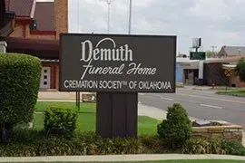 Demuth Funeral Home sign with “Cremation Society of Oklahoma” beside a street and sidewalk
