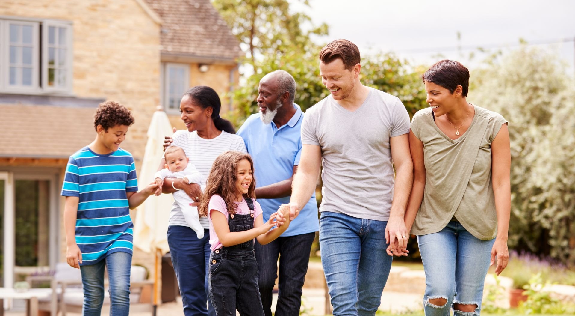 Six people walking together outdoors in a neighborhood, smiling and chatting.