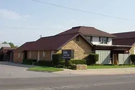 Brick building with maroon roof and sign at a street corner