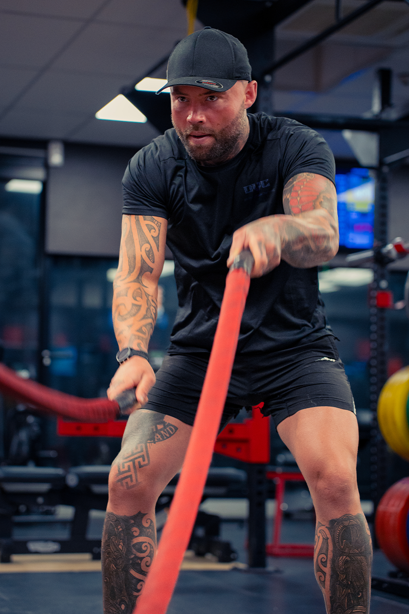A man is holding a red rope in a gym.