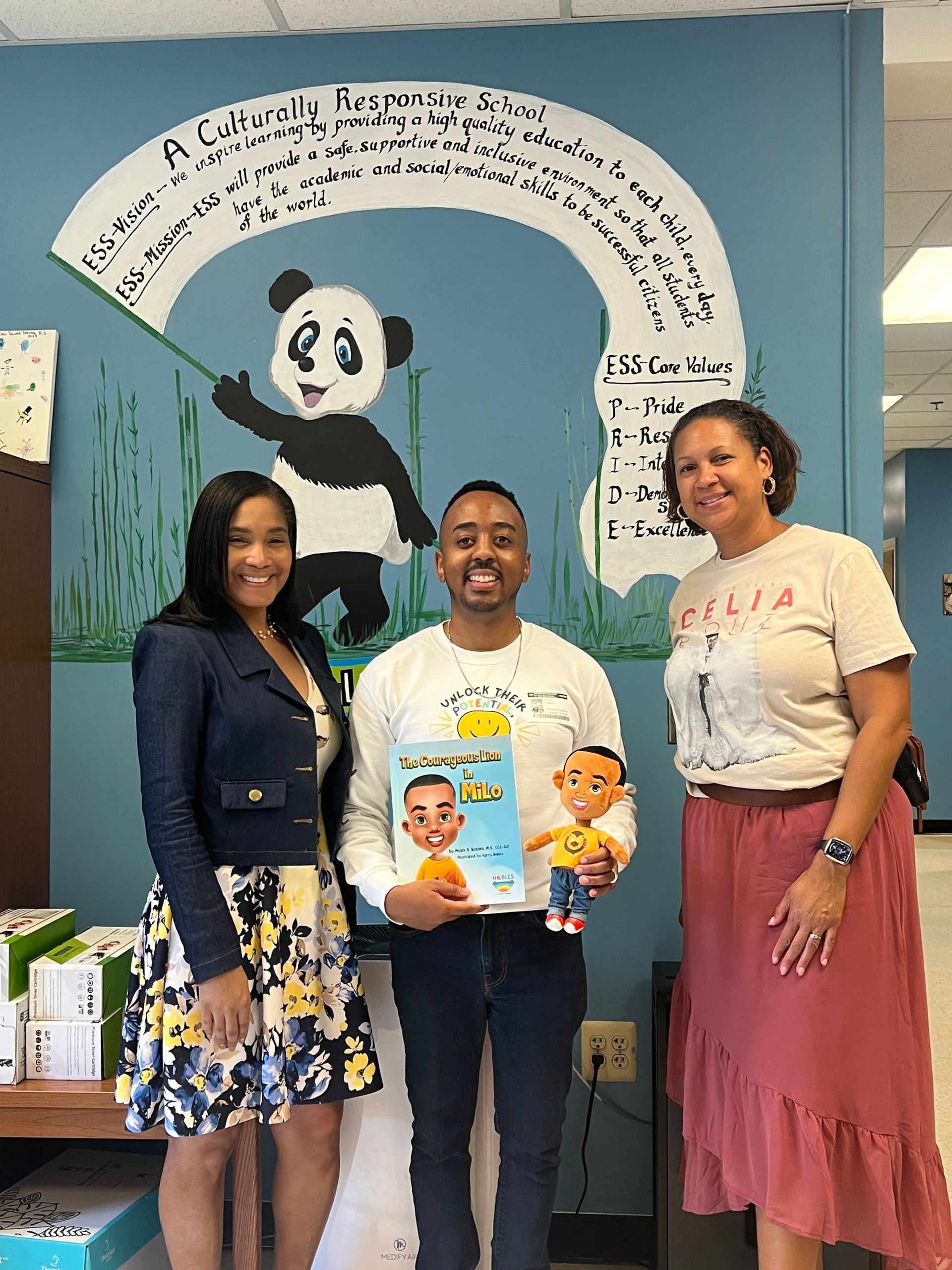 A man and two women are standing next to each other holding a book.