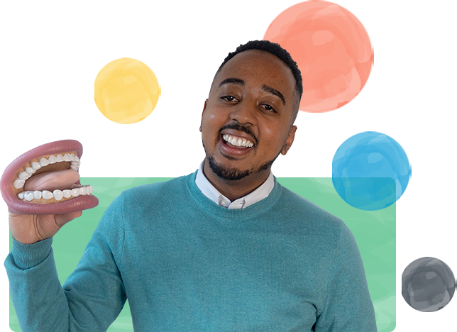 Myles Nobles in a blue sweater is holding a model of teeth