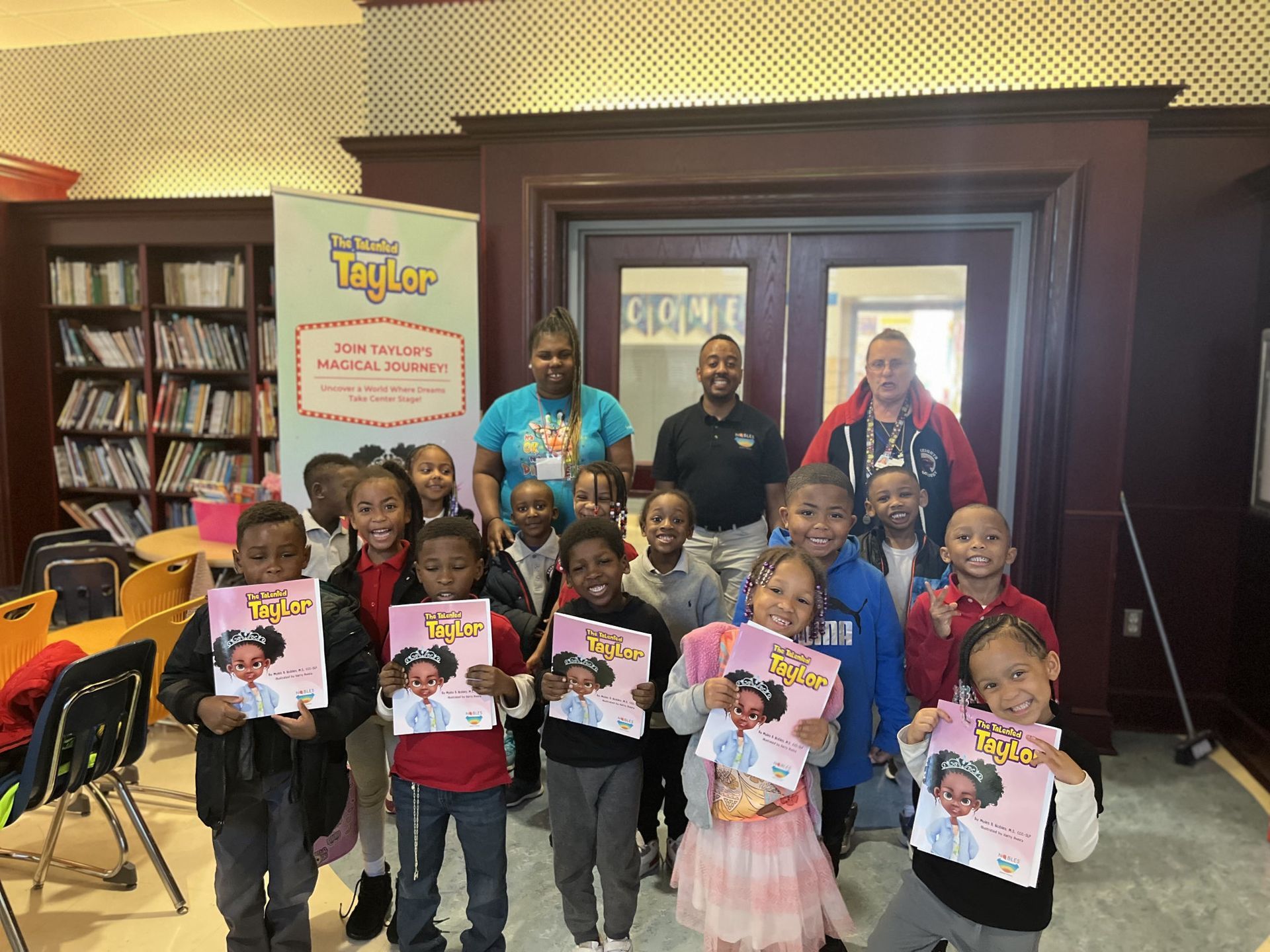 A group of young students holding up children's books in front of a