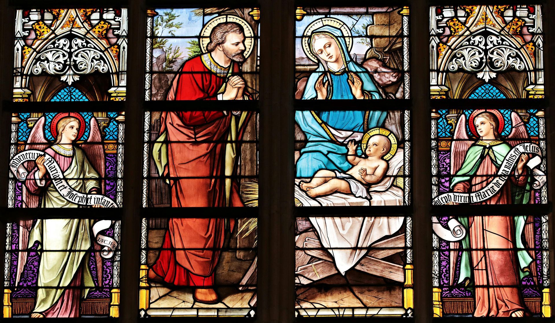 Stained glass window: Joseph looks at angel; Mary and baby Jesus; two angels.