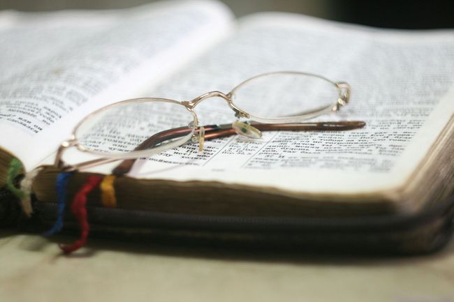 Open book with eyeglasses resting on the pages and colorful bookmarks.