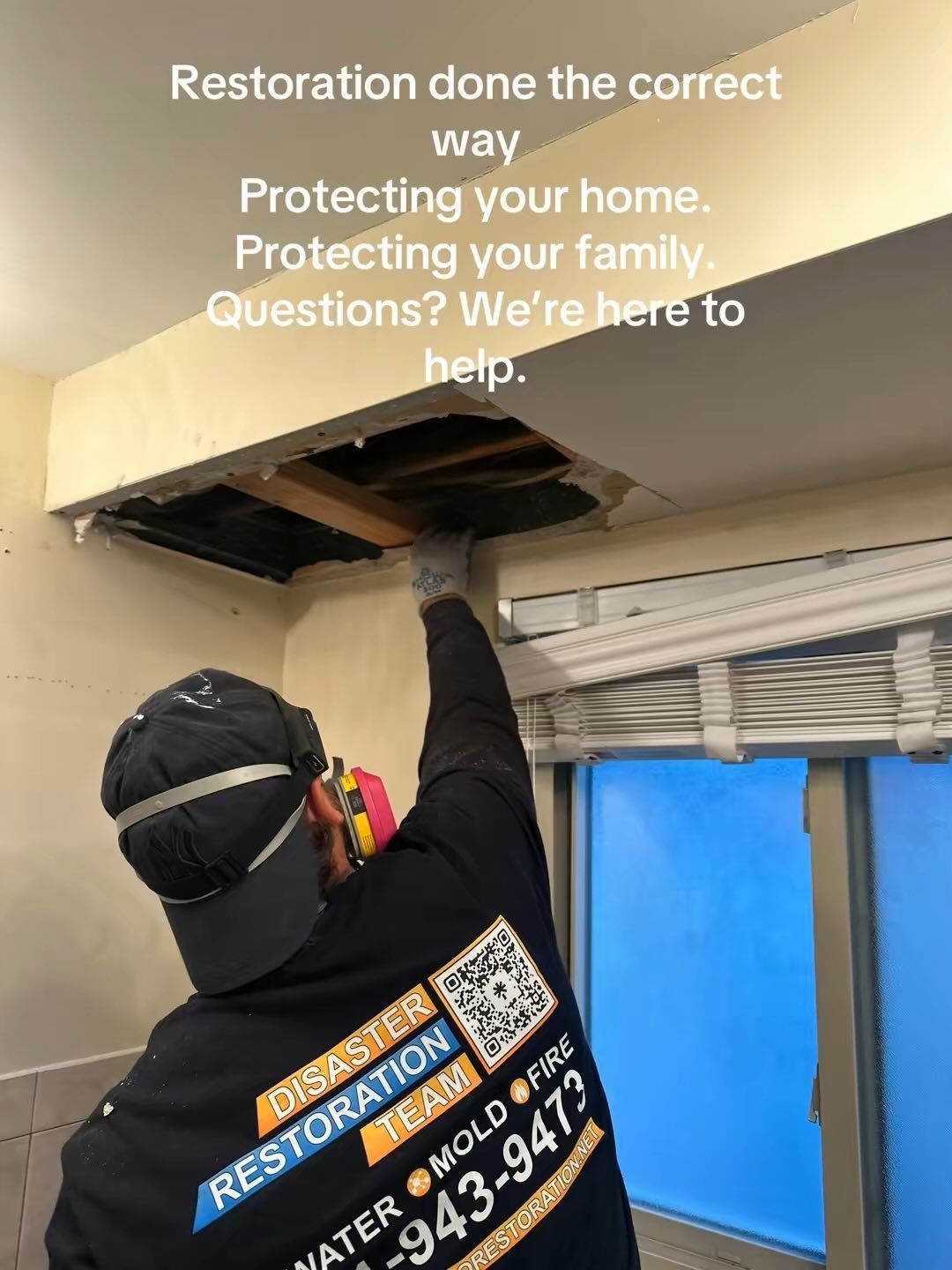 Worker in black jacket repairs a ceiling vent in a room with a partially open window and blue tarp outside.