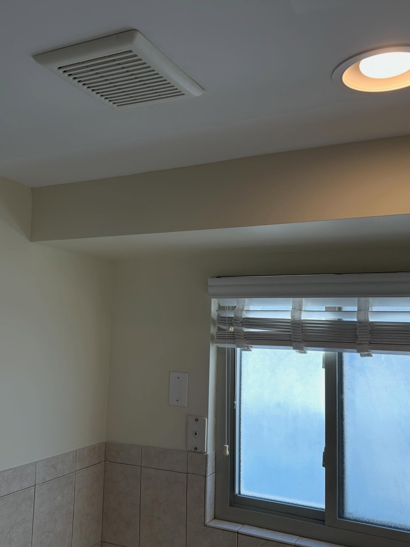 Bathroom with frosted window, beige walls, and ceiling vent and light