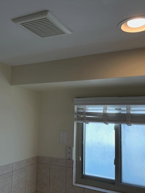 Bathroom with frosted window, beige walls, and ceiling vent and light