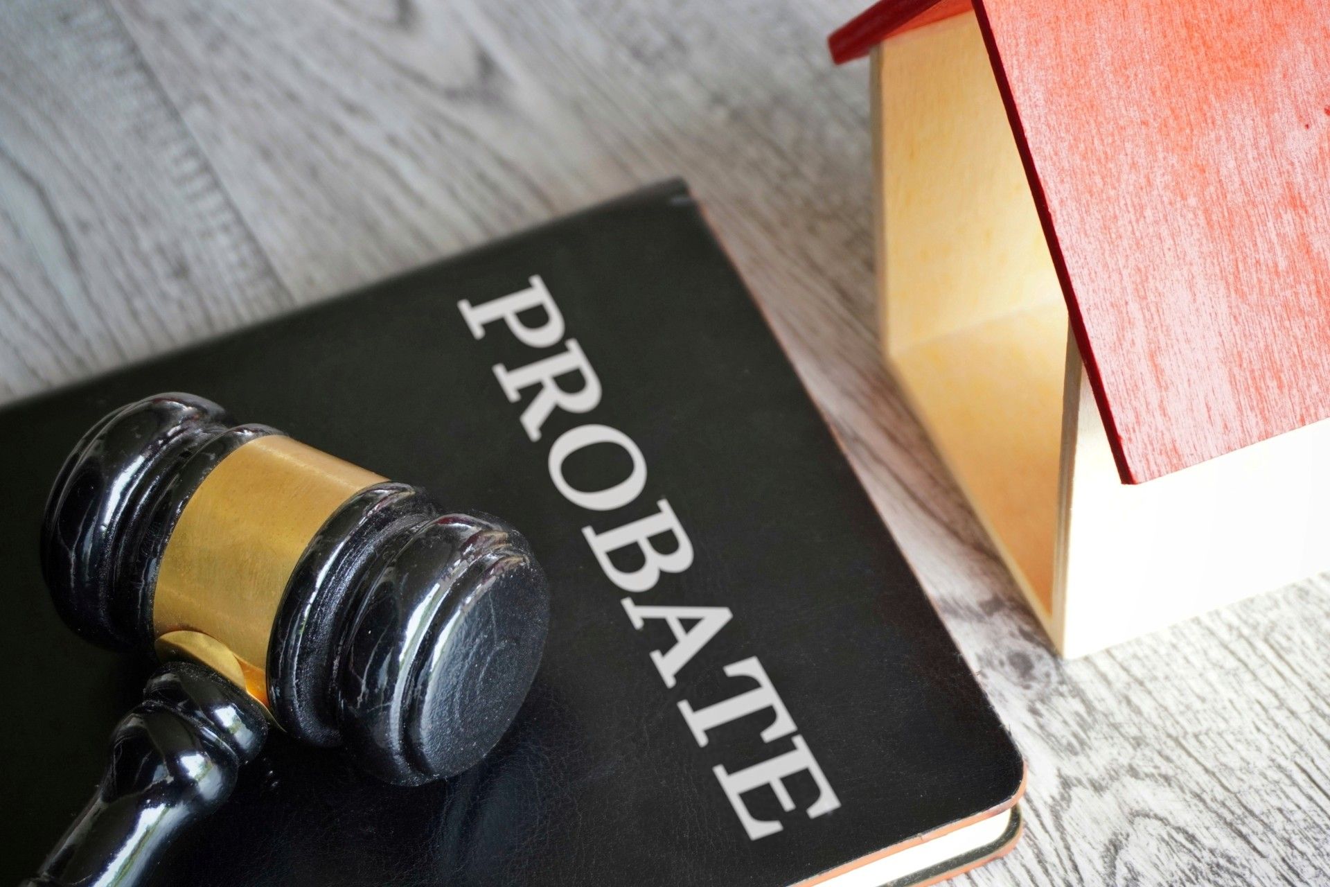 Judge’s gavel on a black “PROBATE” book beside a stack of books on a desk