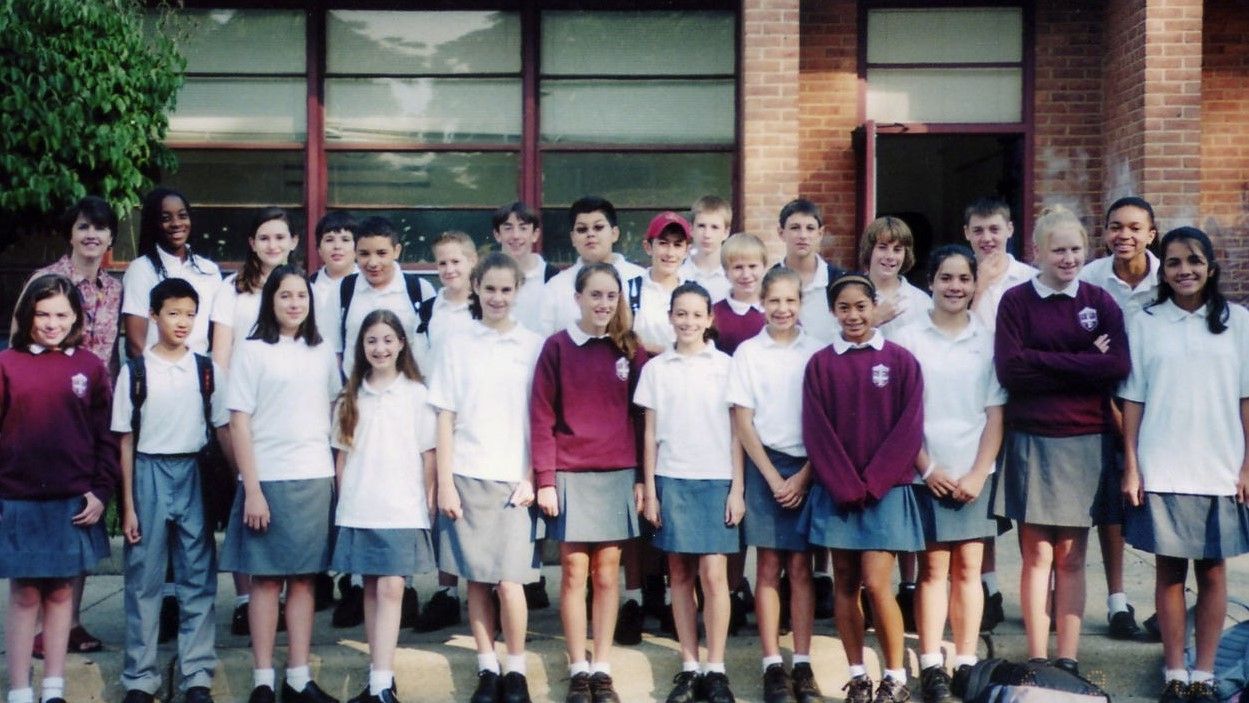 Group of students standing in front of a building, posing for a class photo.