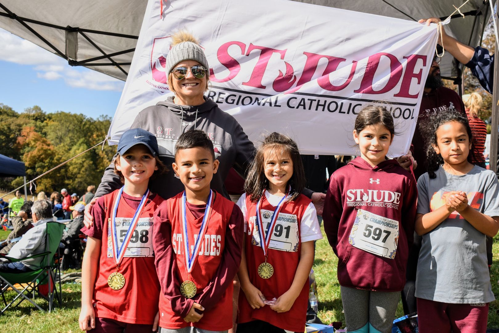 Children in red shirts with medals standing in front of a St. Jude banner outdoors