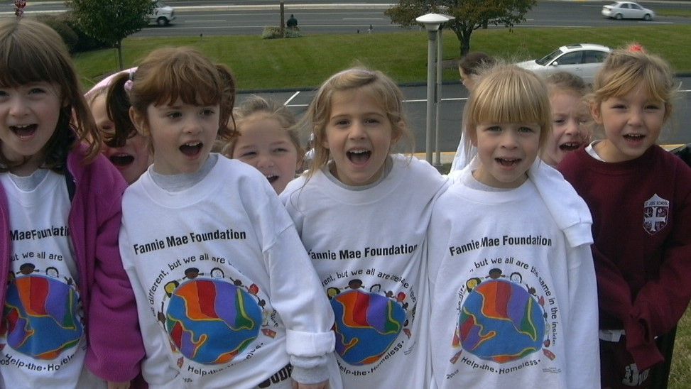 Children in white and maroon hoodies smiling outdoors in a park-like setting