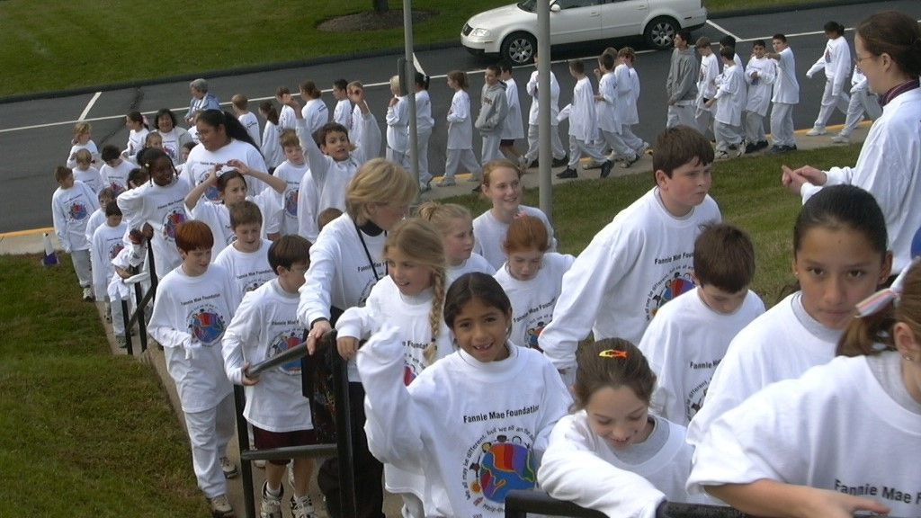 People in white shirts walking up outdoor steps in a group, likely at a community event or race finish.